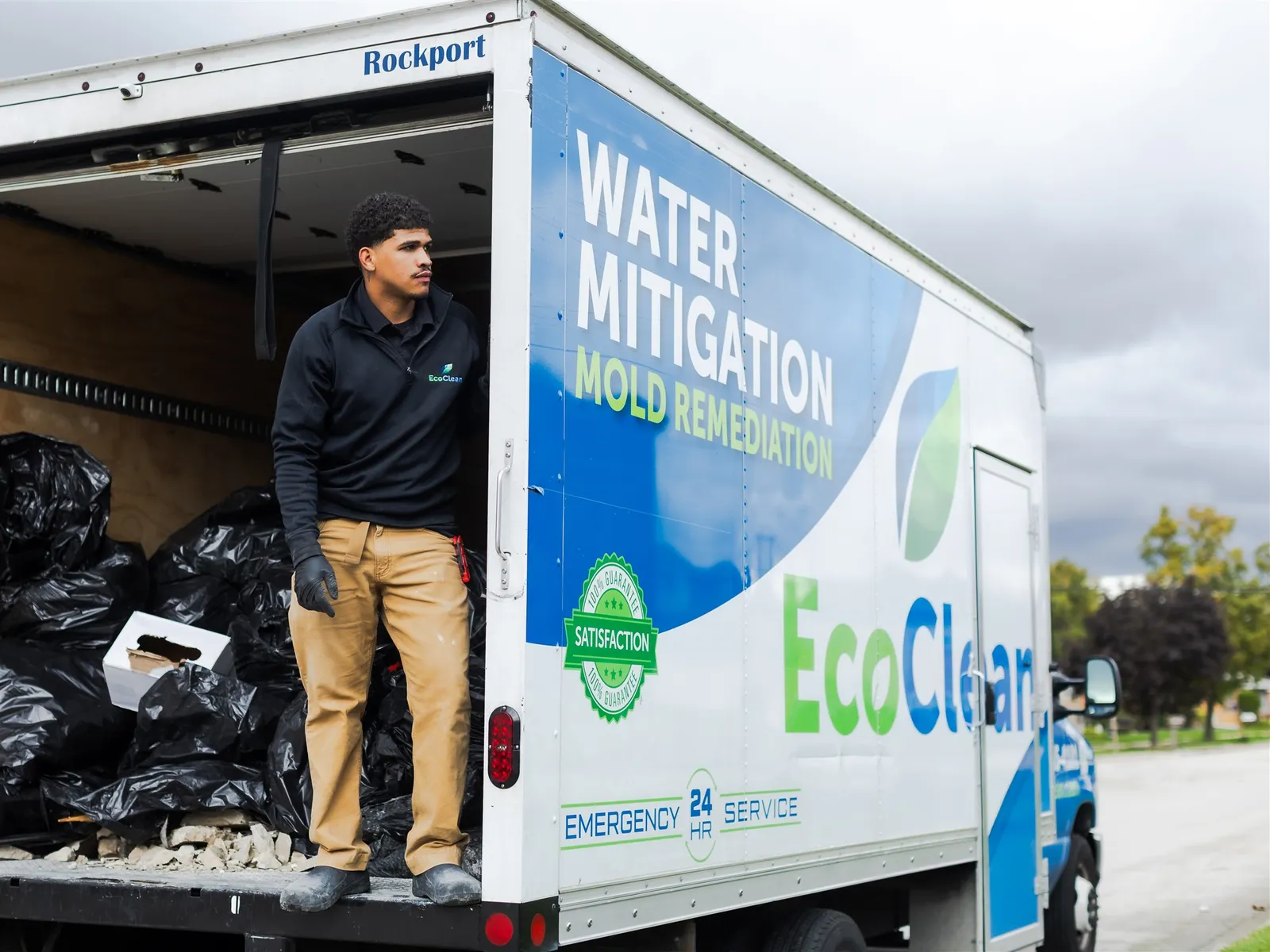 EcoClean crew member standing in the back of the box truck, loaded with debris bags.