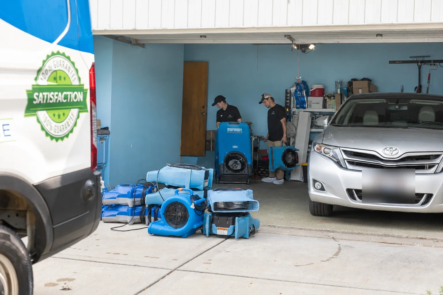 Air movers and a dehumidifier staged in a garage.