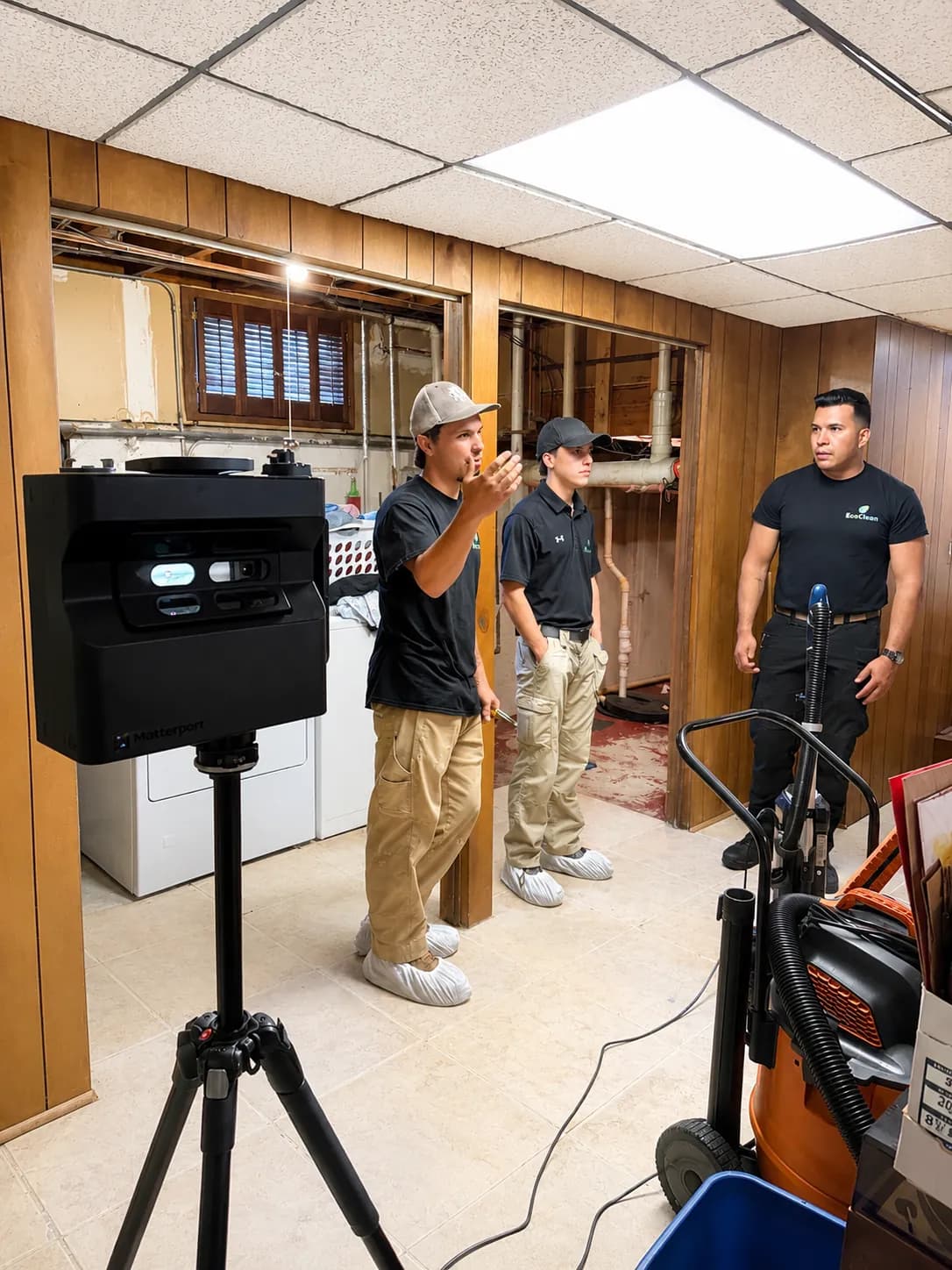 EcoClean crew setting up a Matterport 3D scanner in a partially demoed basement.