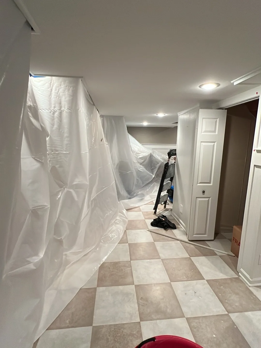 Hallway lined with plastic containment sheeting, with a technician working at the far end.