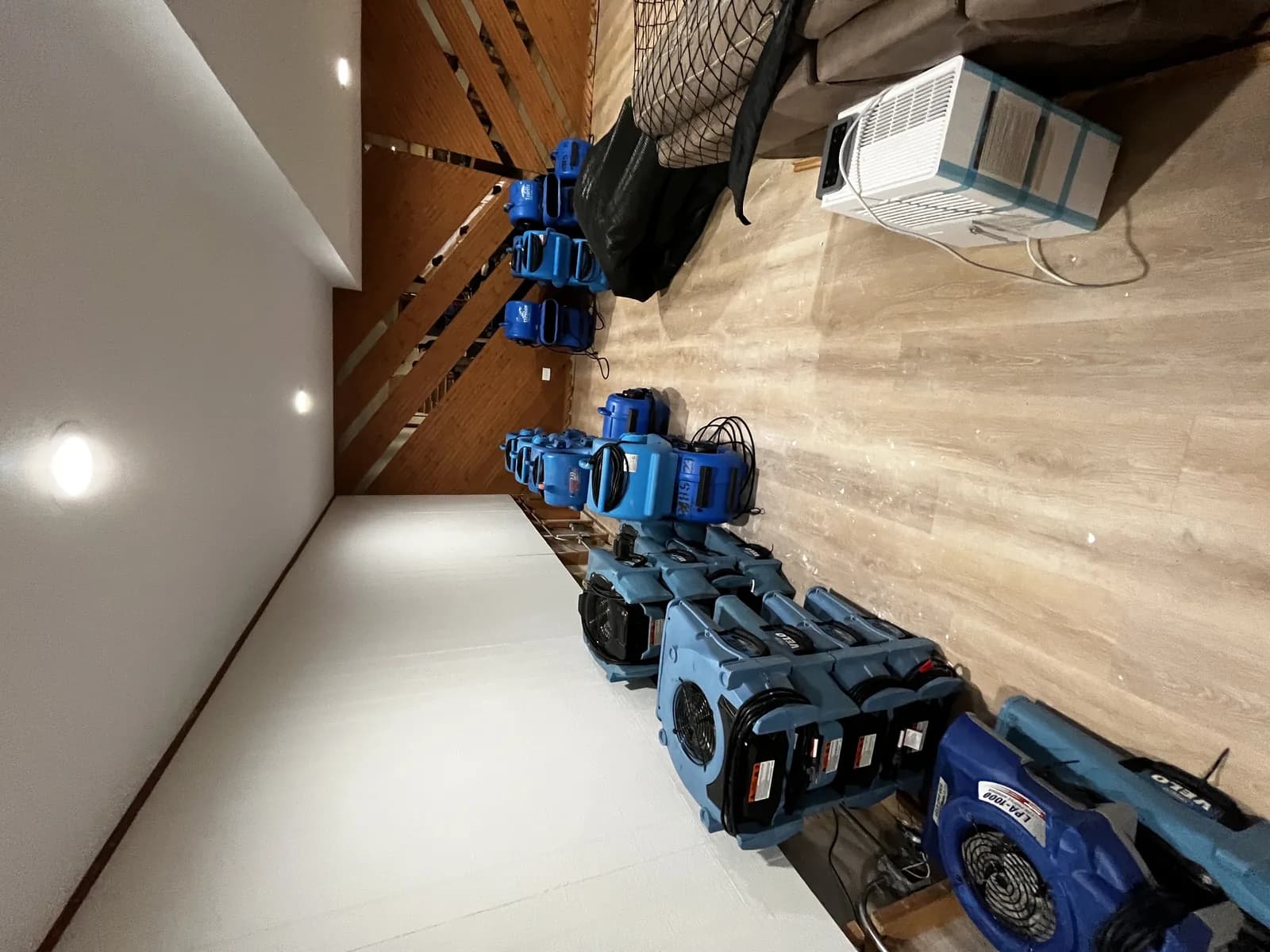 Rows of air movers and dehumidifiers staged for a drying job.