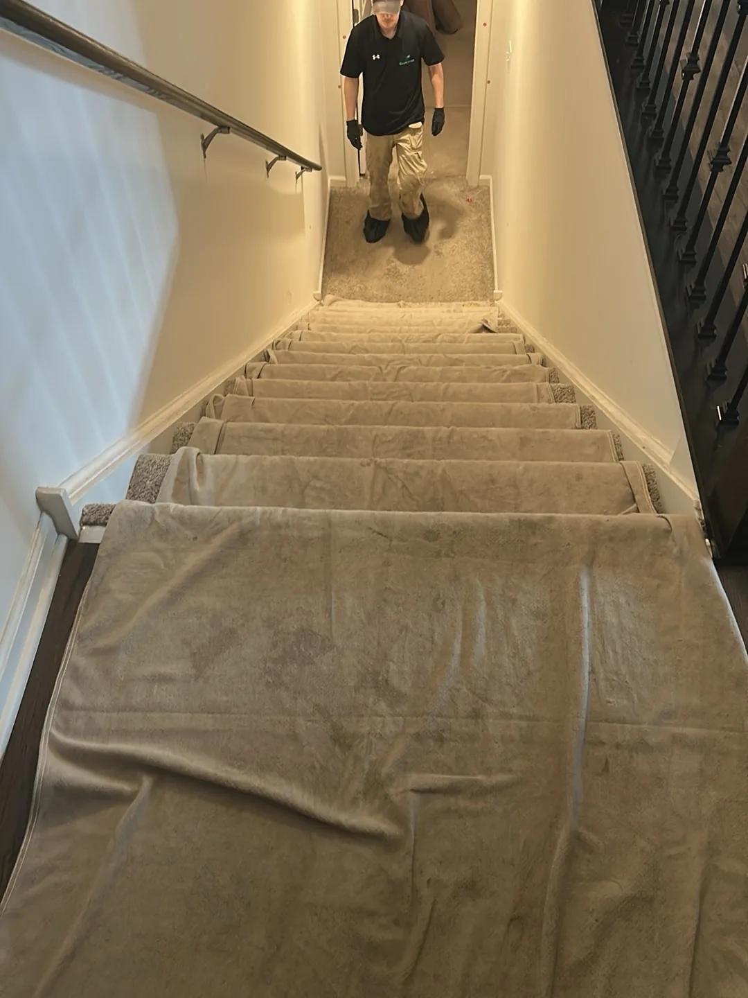 Carpeted staircase covered stair by stair in protective film, with a technician at the top.