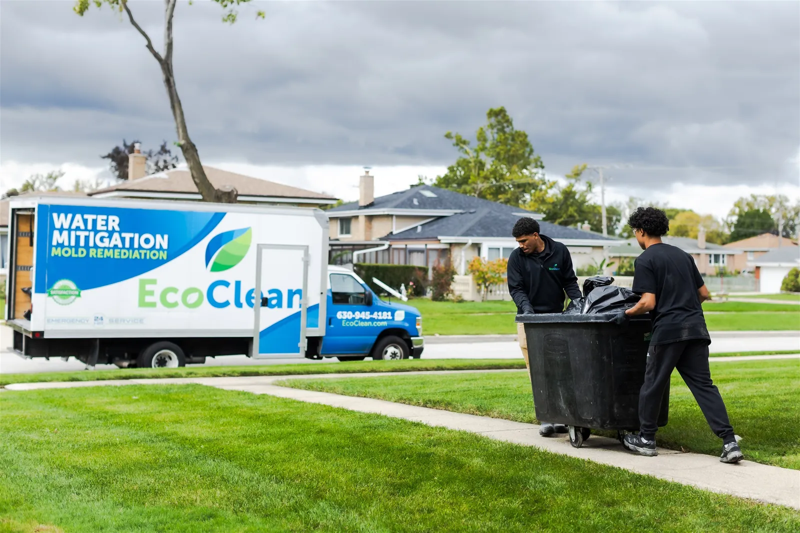 Two EcoClean crew members rolling a debris cart to the EcoClean box truck.